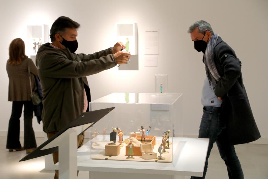   Inauguración Exposición "Miradas Tintinófilas" - Imagen de una persona haciendo una fotografía con su móvil a uno de los objetos de la exposición.