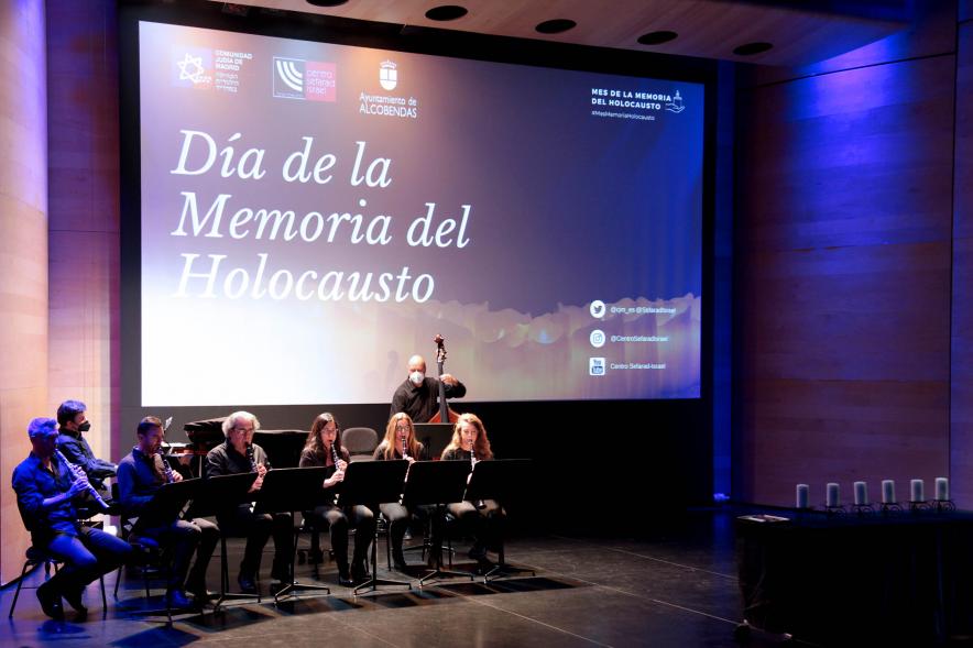  Acto Día de la Memoria del Holocausto 2022 - Plano general del escenario con  el grupo de músicos y la diapositiva del homenaje.