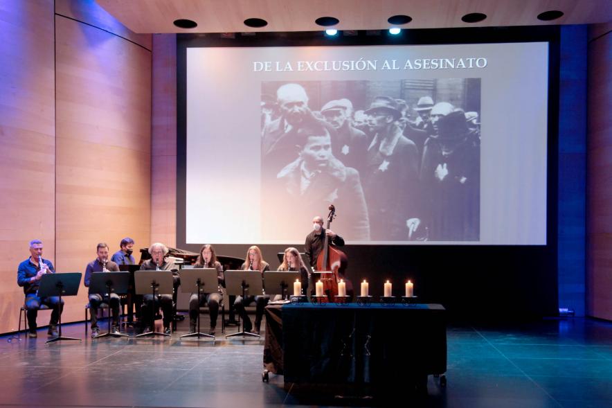Acto Día de la Memoria del Holocausto 2022 - Panorámica del escenario, el grupo musical y una imagen de la barbarie.