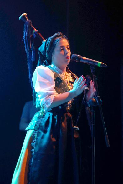 Detalle mujer cantando con gaita al hombro