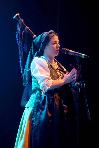 Detalle mujer cantando con gaita al hombro