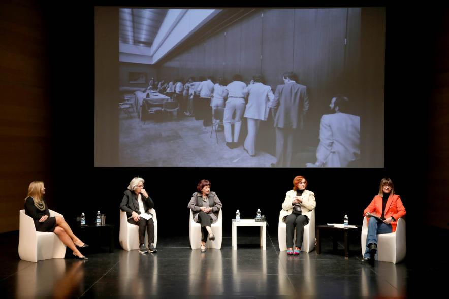 Coloquio y Visita Guiada a la Exposición "Cinco Miradas"  -  Imagen vista panorámica del escenario donde vemos a las participantes en el coloquio.