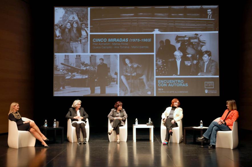 Coloquio y Visita Guiada a la Exposición "Cinco Miradas"  - Imagen vista panorámica del escenario donde vemos a las participantes en el coloquio.