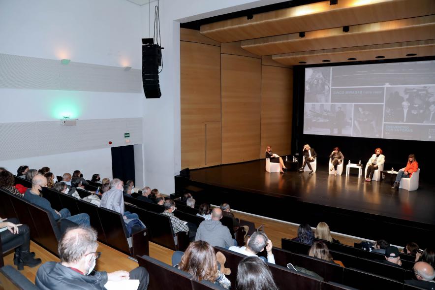 Coloquio y Visita Guiada a la Exposición "Cinco Miradas" -  Imagen panorámica del auditorio Paco de Lucía donde se celebra el coloquio, donde vemos al público asistente y el escenario con las fotoperiodistas.