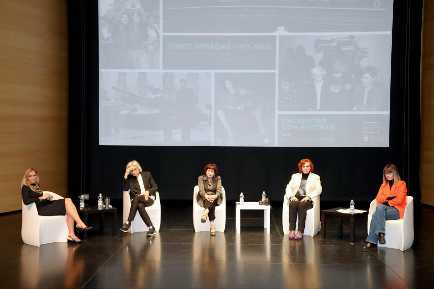 Coloquio y Visita Guiada a la Exposición "Cinco Miradas" -  Imagen panorámica del escenario donde vemos a las participantes en el coloquio.