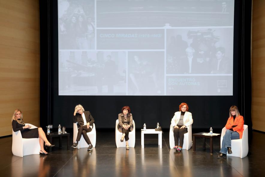 Coloquio y Visita Guiada a la Exposición "Cinco Miradas" -  Imagen panorámica del escenario donde vemos a las participantes en el coloquio.