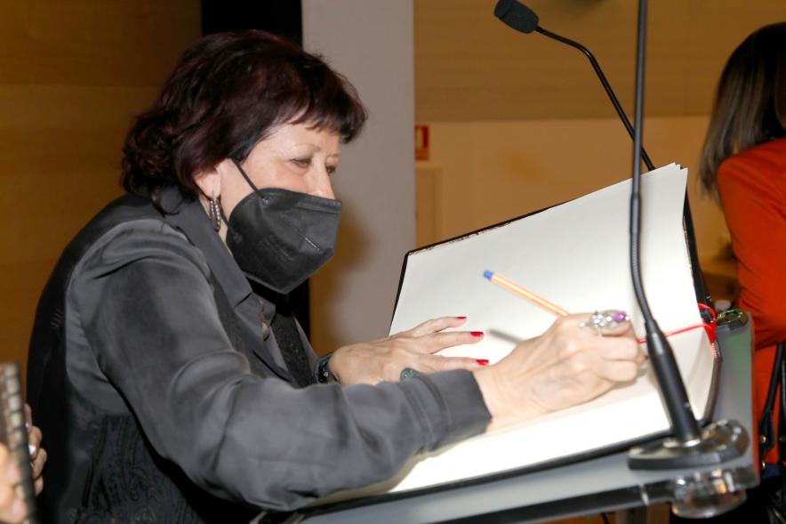 Coloquio y Visita Guiada a la Exposición "Cinco Miradas" -  Imagen de un momento de la firma en el libro de honor de la fotoperiodista Pilar Aymerich.