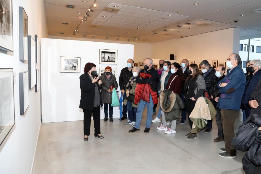 Coloquio y Visita Guiada a la Exposición "Cinco Miradas" - Imagen de Pilar Aymerich realizando la visita guiada de su obra incluida en la exposición “Mujeres Reporteras: Cinco Miradas” y parte del público asistente.