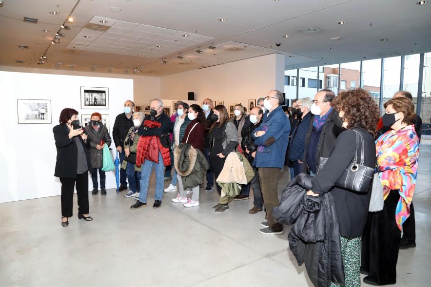 Coloquio y Visita Guiada a la Exposición "Cinco Miradas" - Imagen de Pilar Aymerich realizando la visita guiada de su obra incluida en la exposición “Mujeres Reporteras: Cinco Miradas” y parte del público asistente.