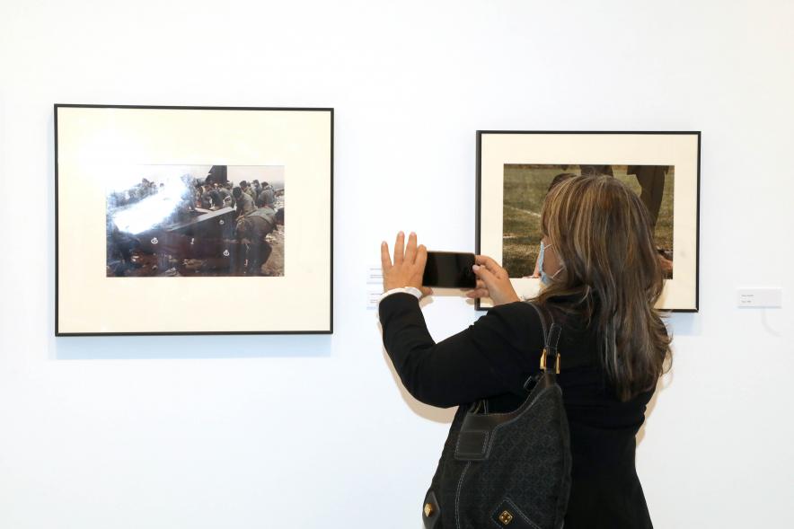  Coloquio y Visita Guiada a la Exposición "Cinco Miradas" - Imagen de una persona realizando una fotografía con su móvil a una de las fotografías expuestas.