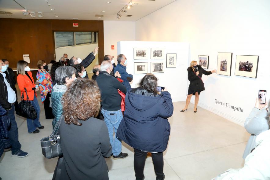  Coloquio y Visita Guiada a la Exposición "Cinco Miradas" - Imagen de la hija de Queca Campillo (Carmen Gutiérrez Campillo) realizando la visita guiada de la obra de su madre incluida en la exposición “Mujeres Reporteras: Cinco Miradas” y parte del público asistente.