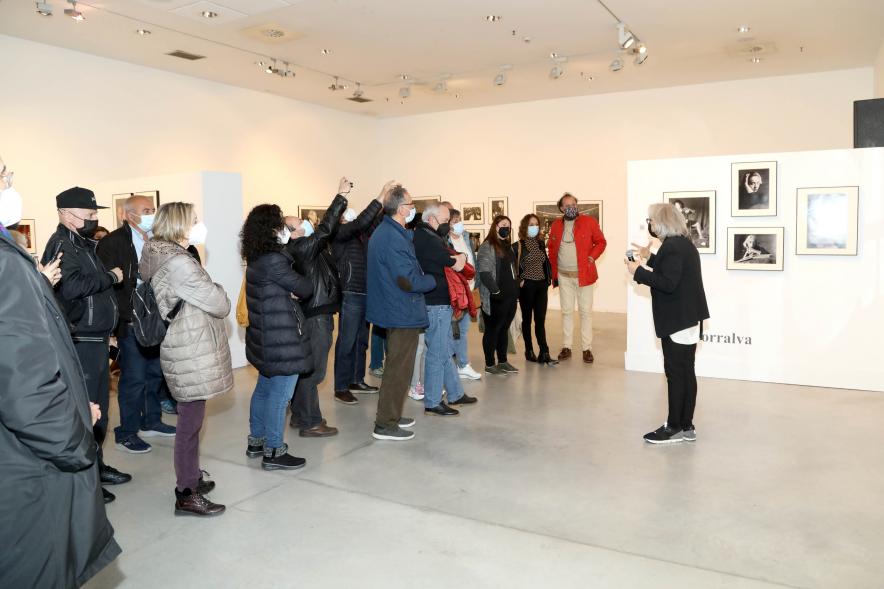 Coloquio y Visita Guiada a la Exposición "Cinco Miradas" - Imagen de Ana Torralva realizando la visita guiada de su obra incluida en la exposición “Mujeres Reporteras: Cinco Miradas” y parte del público asistente.