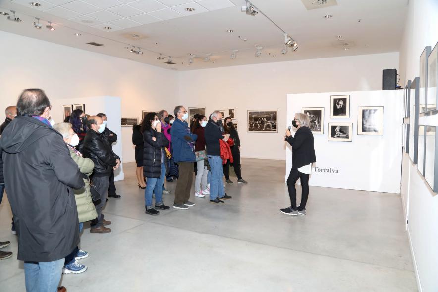 Coloquio y Visita Guiada a la Exposición "Cinco Miradas" -  Imagen de Ana Torralva realizando la visita guiada de su obra incluida en la exposición “Mujeres Reporteras: Cinco Miradas” y parte del público asistente.