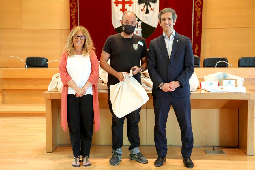   3a Entrega Canastillas Mis Primeros Pasos en Alcobendas - 2022 - Imagen del alcalde Aitor Retolaza y la concejala de Familia Inmaculada Puyalto posando con  una persona que acaba de recibir una canastilla.