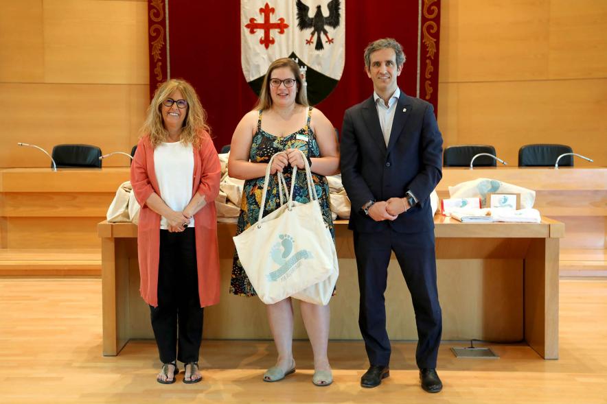   3a Entrega Canastillas Mis Primeros Pasos en Alcobendas - 2022 - Imagen del alcalde Aitor Retolaza y la concejala de Familia Inmaculada Puyalto posando con  una persona que acaba de recibir una canastilla.
