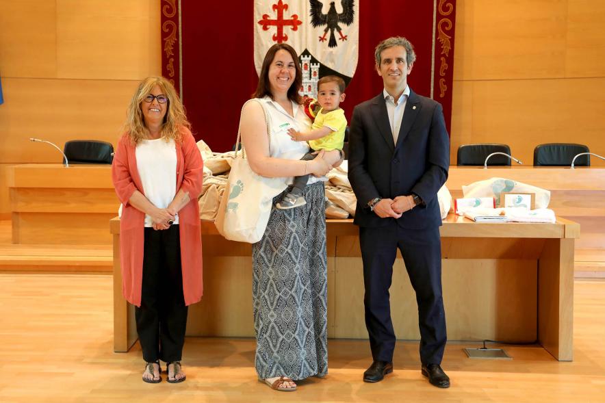  3a Entrega Canastillas Mis Primeros Pasos en Alcobendas - 2022 - Imagen del alcalde Aitor Retolaza y la concejala de Familia Inmaculada Puyalto posando con  una persona que acaba de recibir una canastilla.