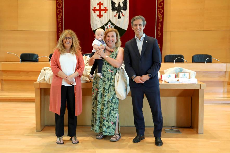  3a Entrega Canastillas Mis Primeros Pasos en Alcobendas - 2022 - Imagen del alcalde Aitor Retolaza y la concejala de Familia Inmaculada Puyalto posando con  una persona que acaba de recibir una canastilla.