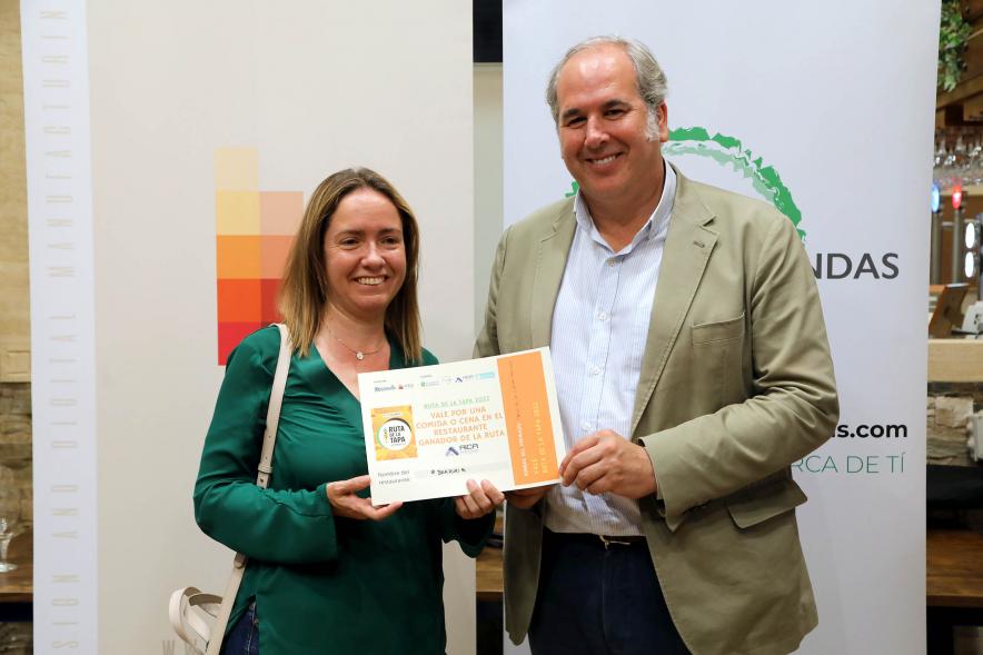 Entrega Premios Ruta de la Tapa 2022 - Imagen de un representante de la Asociación de Comerciantes y Hosteleros La Menina y de AICA haciendo entrega de un premio entre las personas que votaron.