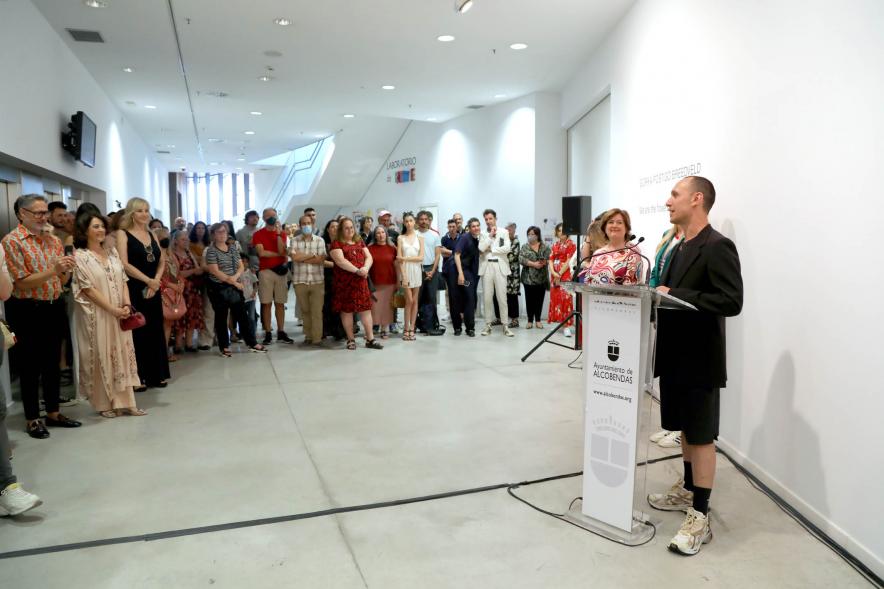 Inauguración Exposición de Gorka Postigo "We Are the Flowers in Your Dustbean" -  Imagen lateral de la sala con el autor hablando y el publico.