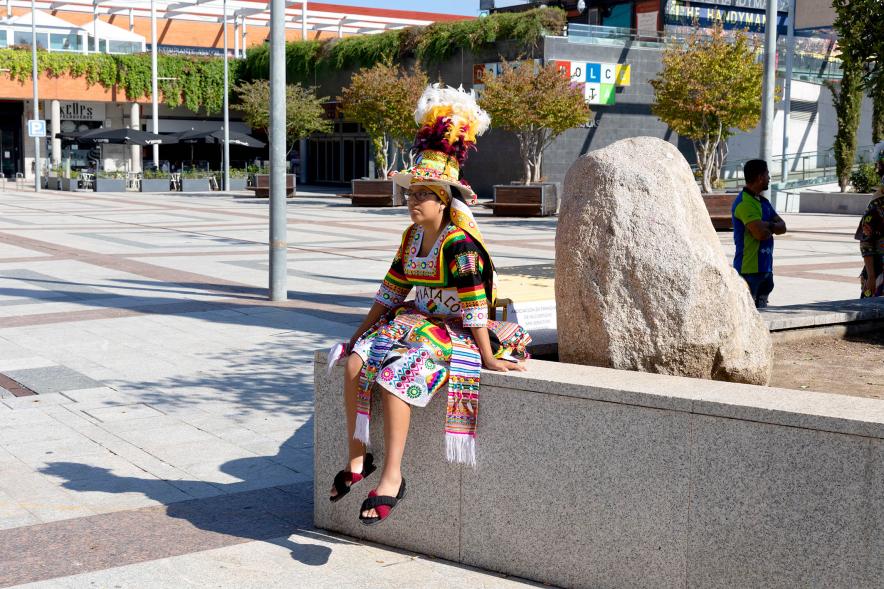 Desfile Festival Intercultural Día de la Hispanidad - Imagen de una joven hispanoamericana descansando.