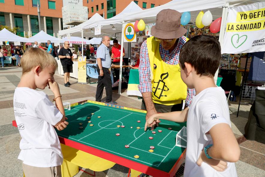 Feria de las Asociaciones 2022 - Imagen  dos niños junto a un futbolín y el monitor de Amnistía Internacional.