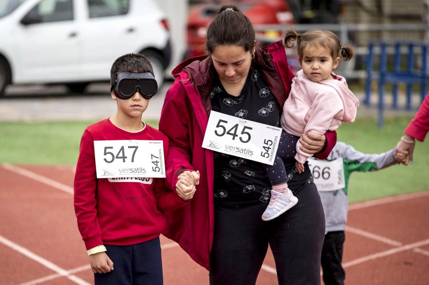 Joven participa en la carrera con gafas de ceguera ayudado por una guía