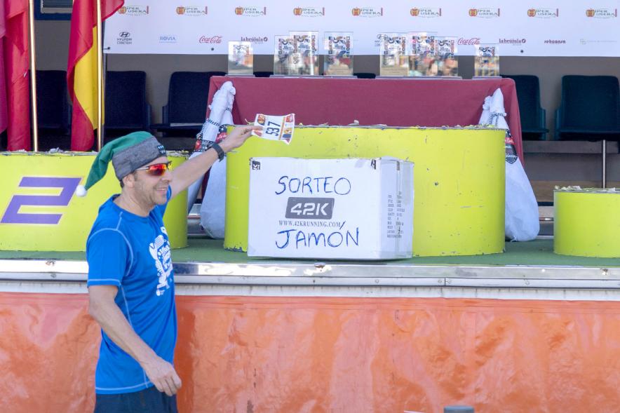 San Silvestre 2022 - Imagen de corredor a su llegada, introduciendo su dorsal en una urna para el sorteo de un jamón.