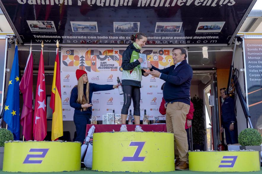 San Silvestre 2022 - Imagen de una corredora en el pódium recibiendo su premio de manos de una autoridad.