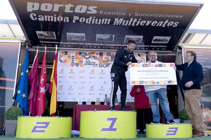 San Silvestre 2022 - Imagen de un corredor en el pódium recibiendo su premio de manos de una autoridad.